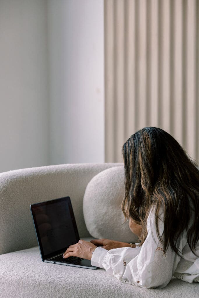 Creative small business owner working on a laptop in a modern, neutral workspace, representing focus and independence while building a website.